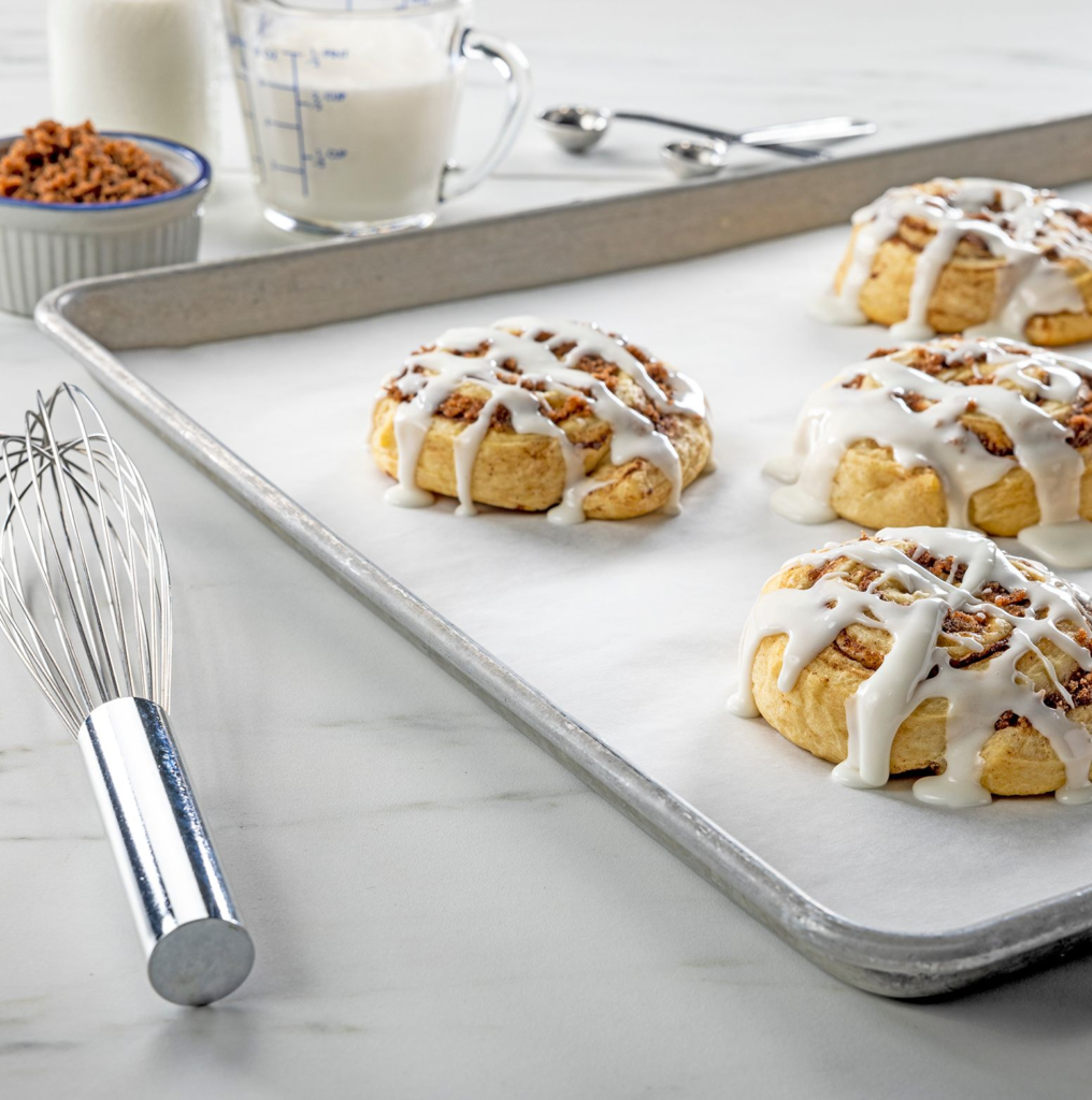 Cinnamon rolls on a baking sheet with parchment paper pan liner
