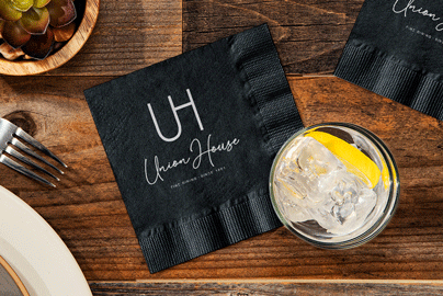 Custom printed cocktail napkin on a tabletop with a cocktail