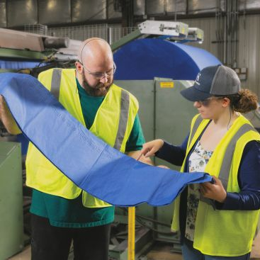 Quality manager and machine operator reviewing tablecover product